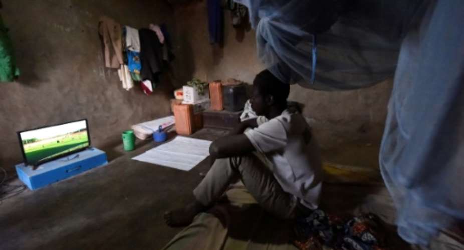 Footy night: Ousmane Kantcho settles down to watch an English Premier League match, thanks to solar energy.  By PIUS UTOMI EKPEI AFP