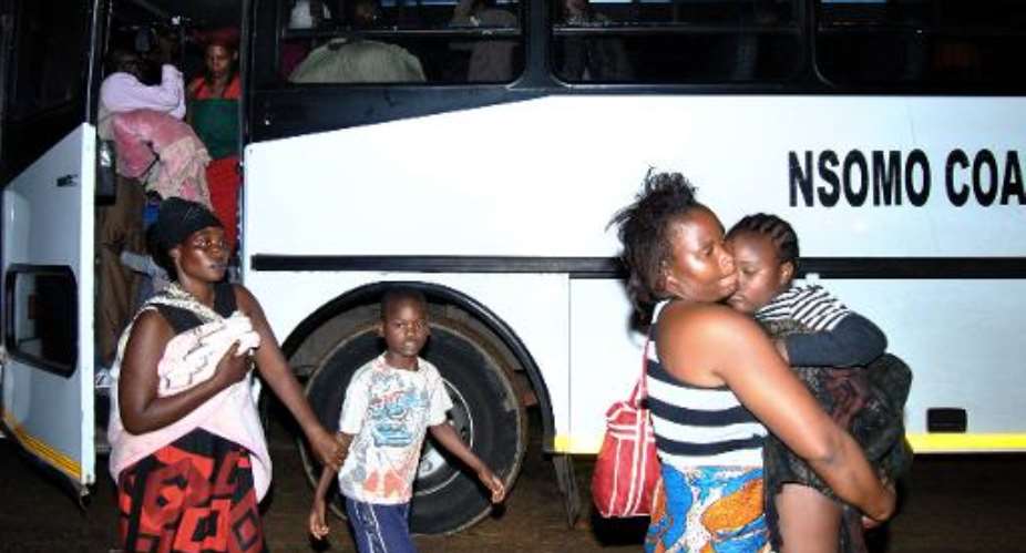 Malawians fleeing xenophobic violence in South Africa disembark a bus in Blantyre on April 20, 2015 after being repatriated.  By Bonex Julius AFP