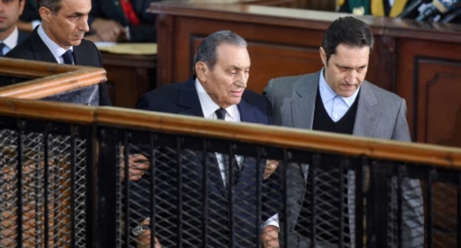 Former Egyptian president Hosni Mubarak C, who was ousted during a popular uprising in 2011, is escorted by his two sons Alaa R and Gamal L for a session in the retrial of members of the now-banned Muslim Brotherhood.  By MOHAMED EL-SHAHED AFPFile