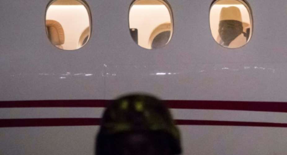 Former president Yaya Jammeh, The Gambia's leader for 22 years, looks through a window from a plane as he leaves the country on January 21, 2017.  By STRINGER AFP