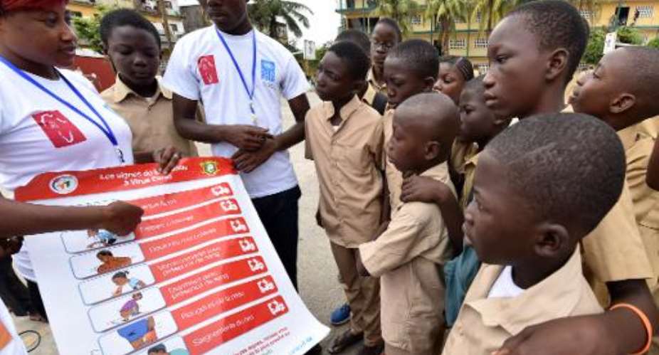 Volunteers wearing t-shirts of the United Nations Development Programme show a placard to raise awareness about the symptoms of the Ebola virus to students in Abidjan, on September 15, 2014.  By Sia Kambou AFPFile