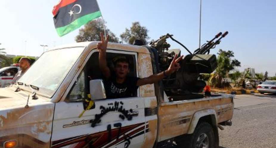 An Islamist fighter from the Fajr Libya Libyan Dawn coalition flashes the V sign for victory at the entrance of Tripoli international airport on August 24, 2014.  By Mahmud Turkia AFPFile