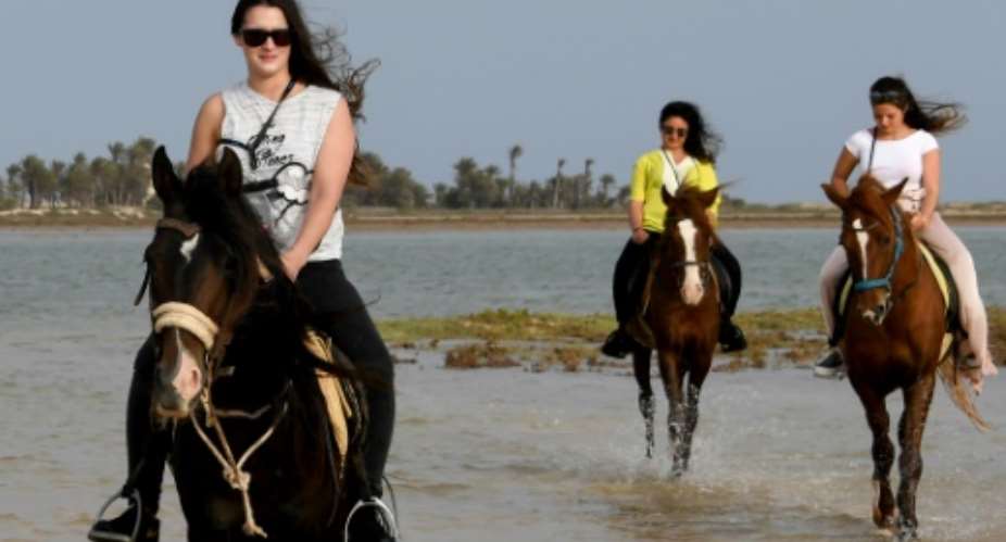 French tourists ride horses along a lagoon on the southern Tunisian resort island of Djerba, on May 13, 2017..  By FETHI BELAID AFP