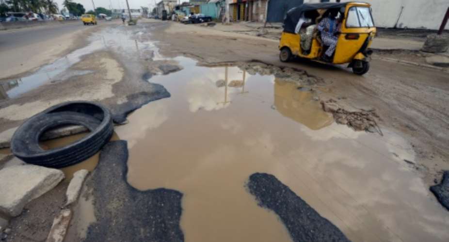 Taxi tricyclists try to avoid waterlogged potholes on Apapa Oshodi expressway in Lagos on October 20, 2014.  By Pius Utomi Ekpei AFPFile