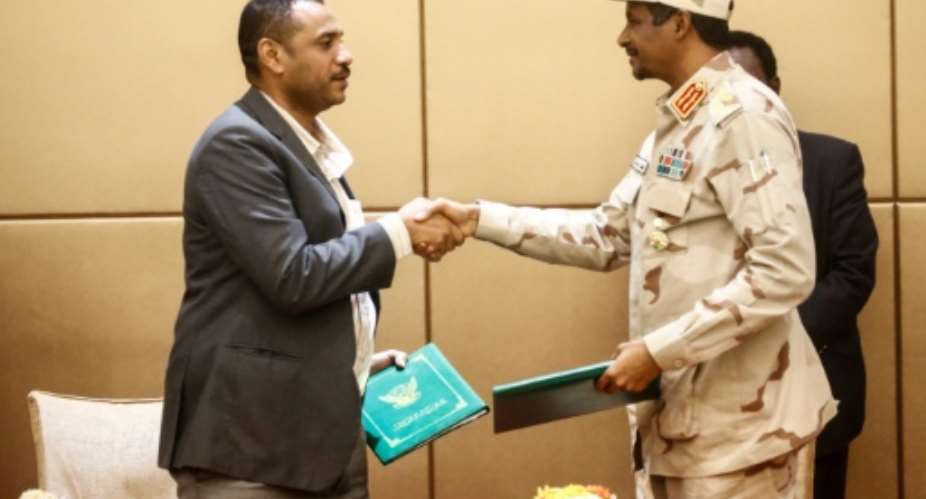 General Mohamed Hamdan Daglo R, deputy head of Sudan's ruling military council, and protest movement leader Ahmed Rabie shake hands after signing the constitutional declaration at a ceremony in Khartoum.  By ASHRAF SHAZLY AFP