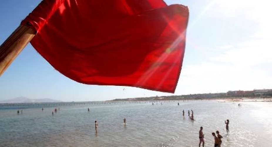 A red flag serving as a warning of shark sightings flutters over tourists on the beach in the Red Sea resort of Sharm el-Sheikh on December 8, 2010.  By  AFPFile