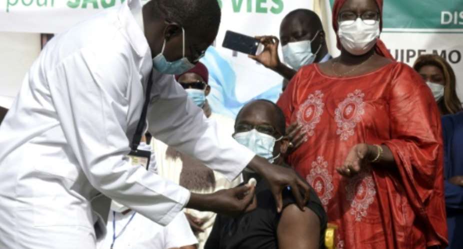 Getting the jab: Health Minister Abdoulaye Diouf Sarr becomes the first person in Senegal to be immunised against coronavirus. The banner reads 'Get vaccinated - protect yourself to save lives'.  By Seyllou AFP