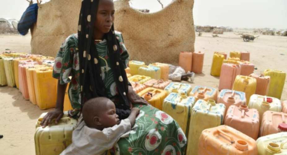 A displaced woman waits with her child for water to be distributed in a refugee camp in Niger.  By Issouf Sanogo AFP