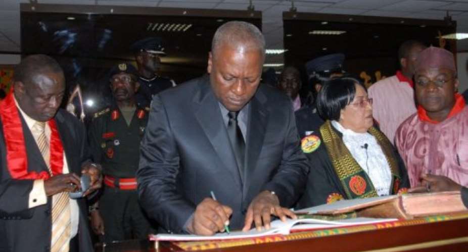 Ghana's Vice President John Dramani Mahama C signs documents after taking the oath of office as head of state.  By Adadevoh David AFP