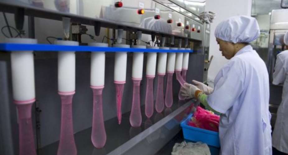 A worker squeezes randomly picked condoms to check for leakages on January 22, 2013 at a factory in Malaysia.  By Saeed Khan AFPFile