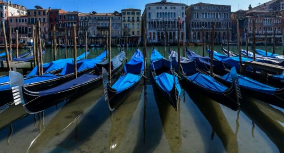 Gondolas sit empty in Venice's Grand Canal with Italy in lockdown to confront the dire impact of new coronavirus which, in one day, killed 475 more people in the country.  By ANDREA PATTARO AFP