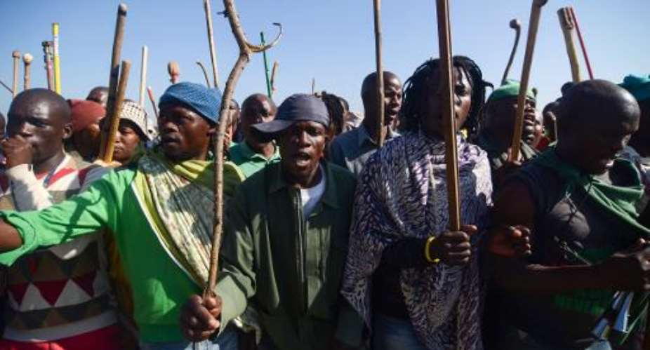 Striking miners hold sticks as they dance and sing during a protest against their labour conditions, in the Wonderkop stadium in Marikana, South Africa, on May 14, 2014.  By Skyler Reid (AFP/File)