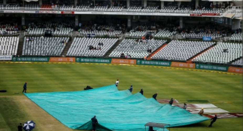 Grounds staff remove tarpaulin from the crease on day three of the first Test match between South Africa and India, which was called off due to rain.  By MARCO LONGARI AFP