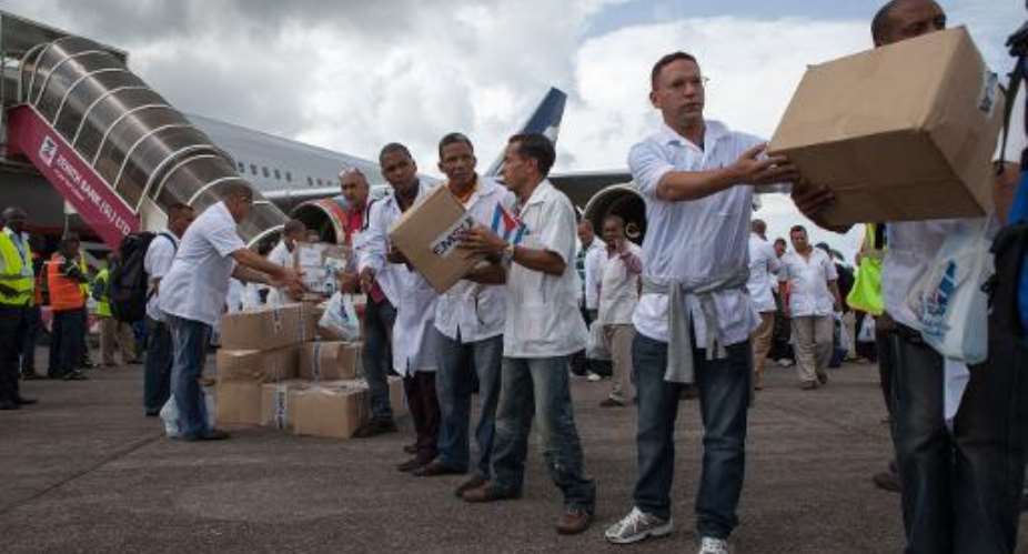 Members of a team of 165 Cuban doctors and health workers unload boxes of medical material upon their arrival in Sierra Leone to help fight Ebola on October 2, 2014.  By Florian Plaucheur AFPFile