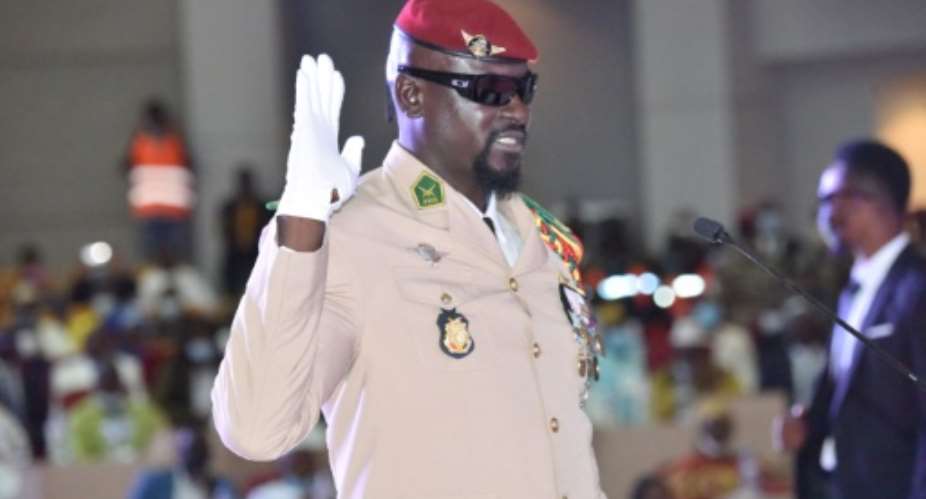 Guinea junta leader Colonel Mamady Doumbouya, raises his hand at his swearing-in ceremony on October 1, 2021 in Conakry.  By Cellou BINANI AFPFile