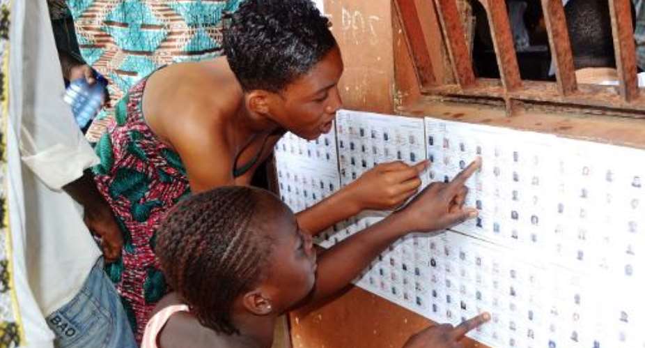 Guinean women search for their names on the registered voters list at a polling station in Conakry on September 28, 2013.  By Cellou Binani (AFP)
