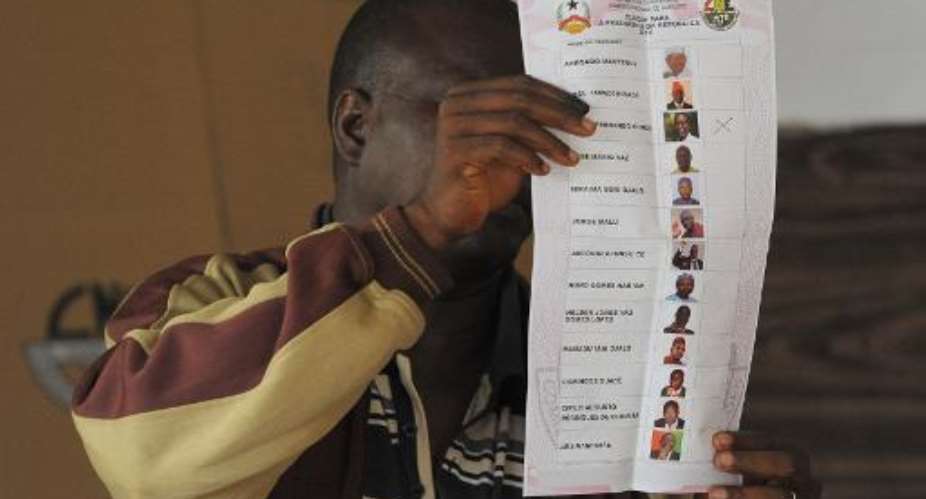 An election official shows a ballot at a polling station in Bissau, Guinea-Bissau, on April 13, 2014.  By Seyllou AFPFile