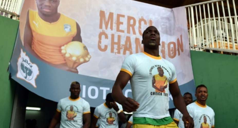 Guinea's players wearing tee-shirts with a picture of Cheick Tiote enter the stadium under a poster reading, Thank you Champion'' prior to the start of the 2019 African Cup of Nations qualifier football match in Bouake on June 10, 2017.  By ISSOUF SANOGO AFPFile