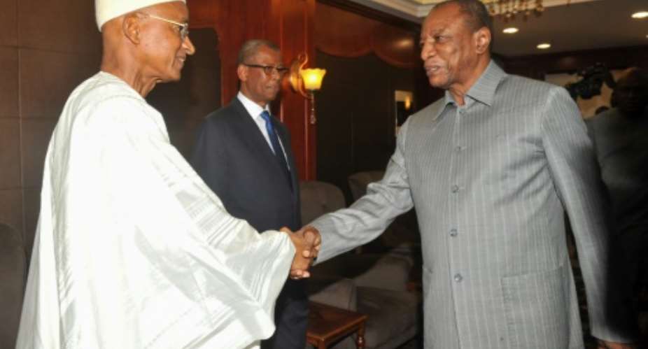 Guinea's President Alpha Conde R shakes hands with opposition leader Cellou Dalein Diallo during their meeting at the presidential palace in Conakry.  By Cellou Binani AFP