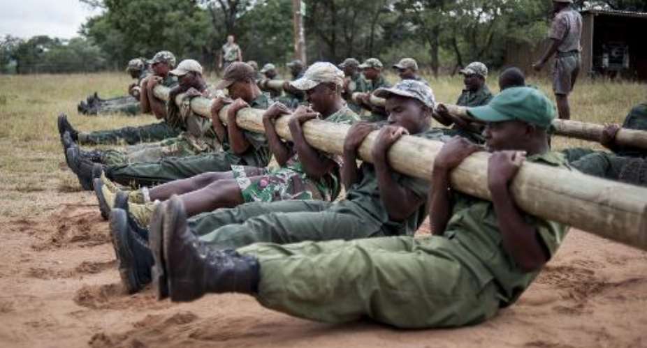 Rangers and new recruits train with heavy wooden poles at the Nkwe Wildlife and Security Services as part of their Op-Fok training to become anti-poaching officers in Vaalwater, in Limpopo Province, on March 17, 2015.  By Stefan Heunis (AFP)