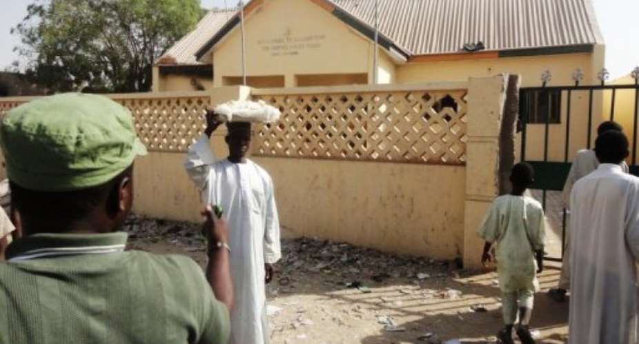 A street vendor passes by a partially burnt police station in the northern Nigerian city of Kano in January 2012.  By Aminu Abubakar (AFP/File)