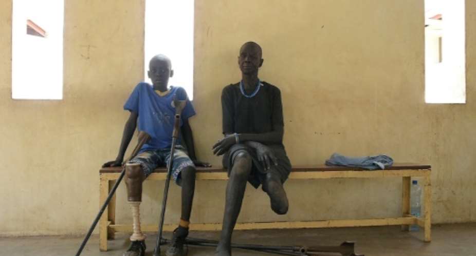 Gunshot wound survivors Jal Keat, 12, left, and Nyagn Thyuong, wait at the Red Cross rehabilitation centre in Juba.  By SIMON MAINA AFP