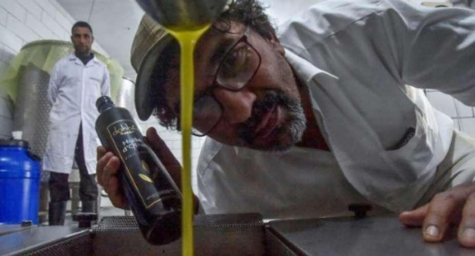 Hakim Alileche inspects a dripping batch of his prize-winning organic olive oil at the press.  By Ryad KRAMDI AFP