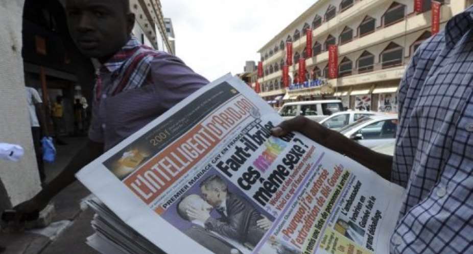 A vendor holds copies of the Intelligent dAbidjan newspaper in Abidjan on May 30, 2013.  By Sia Kambou (AFP/File)
