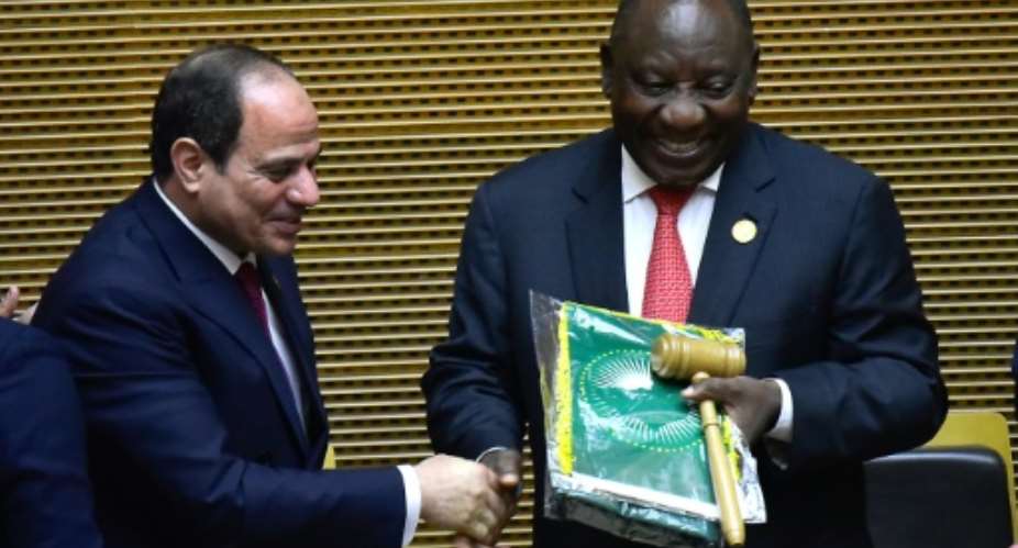 Handover: Outgoing AU chair Egyptian President Abdel Fattah al-Sisi, left, passes the baton to South African President Cyril Ramaphosa. Ramaphosa says settling the conflicts in Libya and South Sudan will be a priority of his tenure.  By MICHAEL TEWELDE AFP
