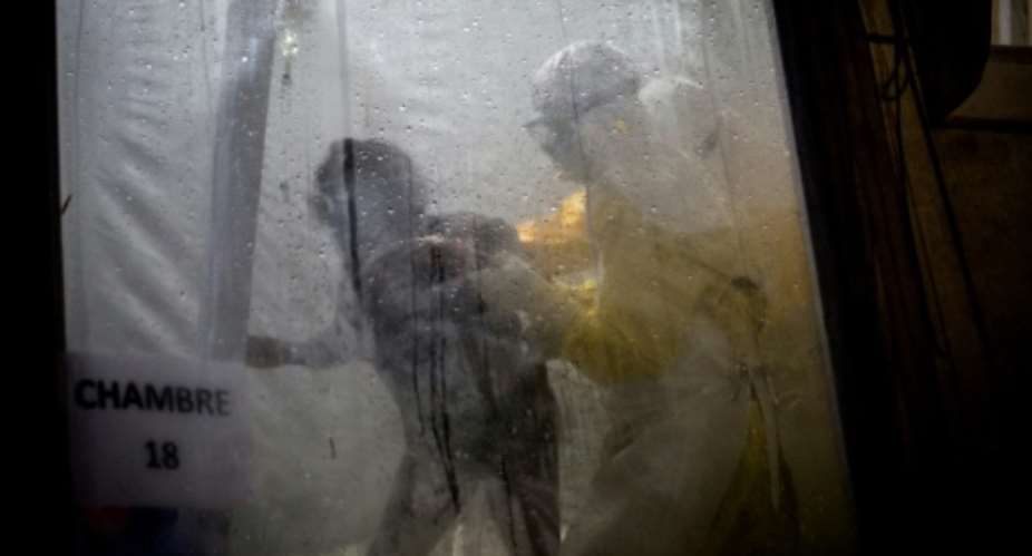 Health workers assist a possible Ebola patient into her bed at an Ebola treatment center supported by the Doctors Without Borders group in Butembo, in the Democratic Republic of the Congo.  By John WESSELS AFPFile