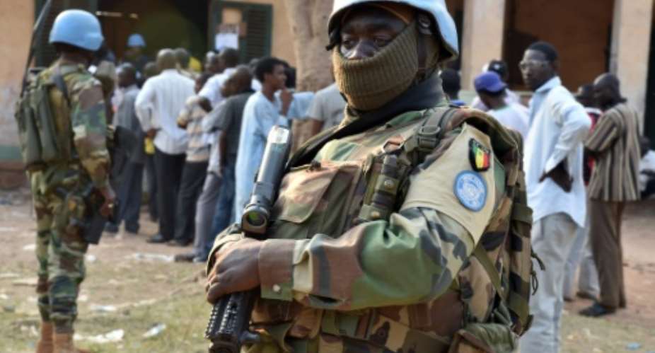 Senegalese UN peacekeeping forces stand guard as people wait to vote at a polling station during presidential and legislative elections in Bangui on December 30, 2015.  By Issouf Sanago AFP
