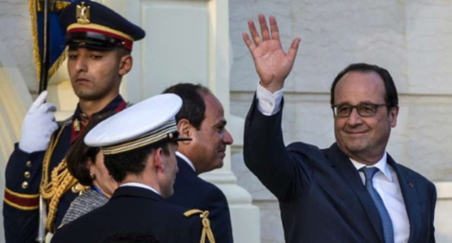 French President Francois Hollande R waves next to Egyptian counterpart Abdelfattah al-Sisi C after reviewing the honour guard during a welcome ceremony at the al-Quba presidential palace in Cairo on April 17, 2016.  By Khaled Desouki AFP