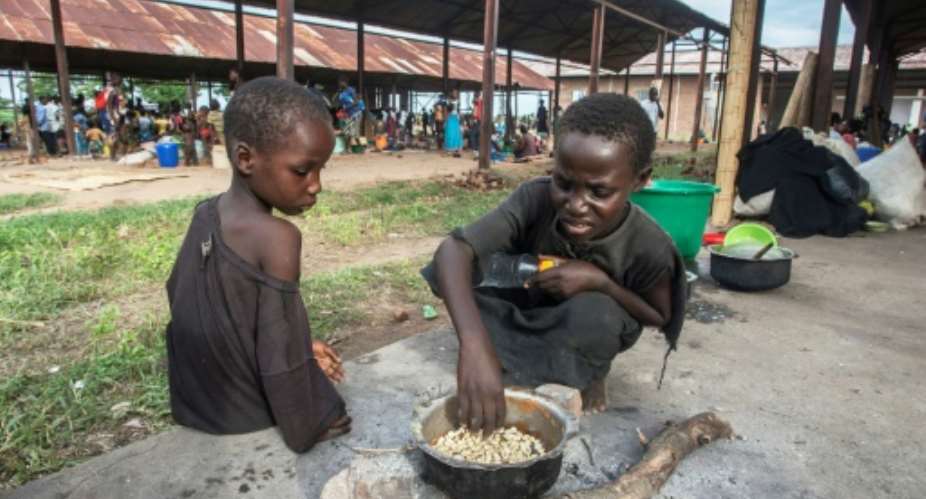 Homeless: Children cook corn at a camp for displaced people in Bangula, southern Malawi.  By AMOS GUMULIRA AFP