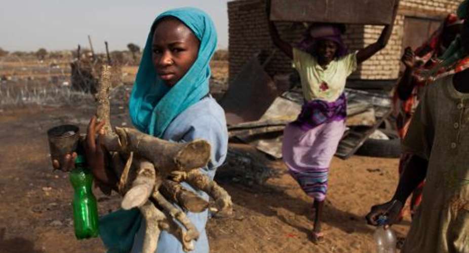 Displaced women carry firewood and other belongings into the United Nations-African Union Mission in Darfur base in Khor Abeche, South Darfur, April 7, 2014.  By Albert Gonzalez Farran UNAMIDAFP