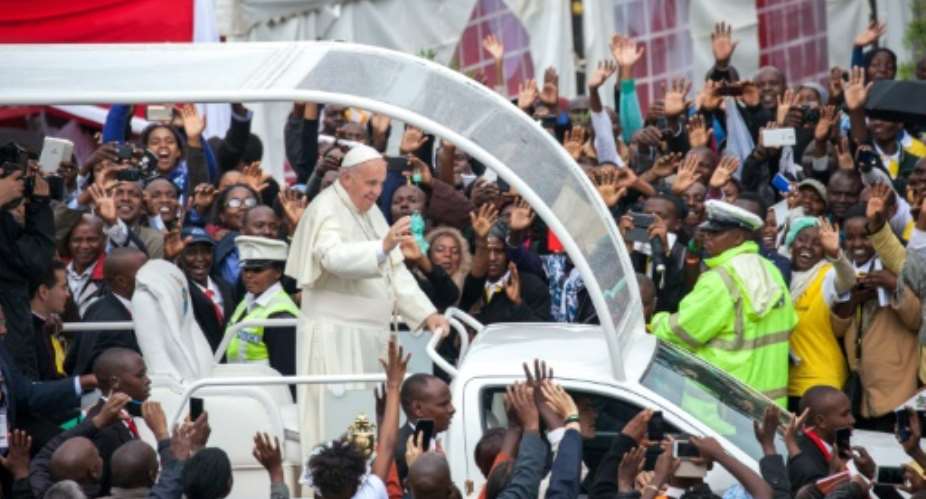 Pope Francis waves to the crowd at the University of Nairobi as he arrives to deliver a huge open-air mass on November 26, 2015.  By Georgina Goodwin AFP