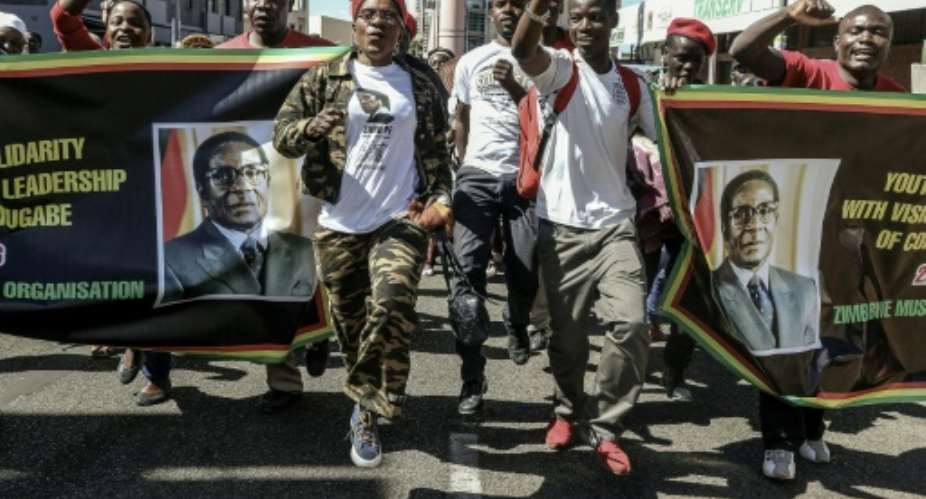 Supporters of Zimbabwean President Robert Mugabe march through Harare during a pro-regime rally on May 25, 2016.  By Jekesai Njikizana AFP
