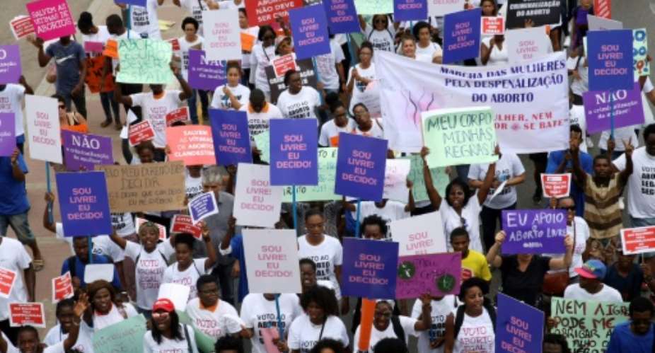 Hundreds of Angolans hold placards and shout slogans as they march to protest against a draft law that would criminalise all abortions.  By AMPE ROGERIO AFP