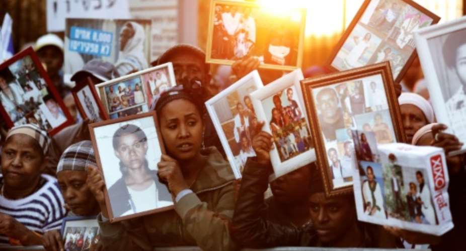 Hundreds of Israelis from the Jewish Ethiopian community hold up photographs of relatives outside the parliament in Jerusalem on March 12, 2018 during a demonstration demanding the state allow their family members in Ethiopia to join them in Israel.  By MENAHEM KAHANA AFP