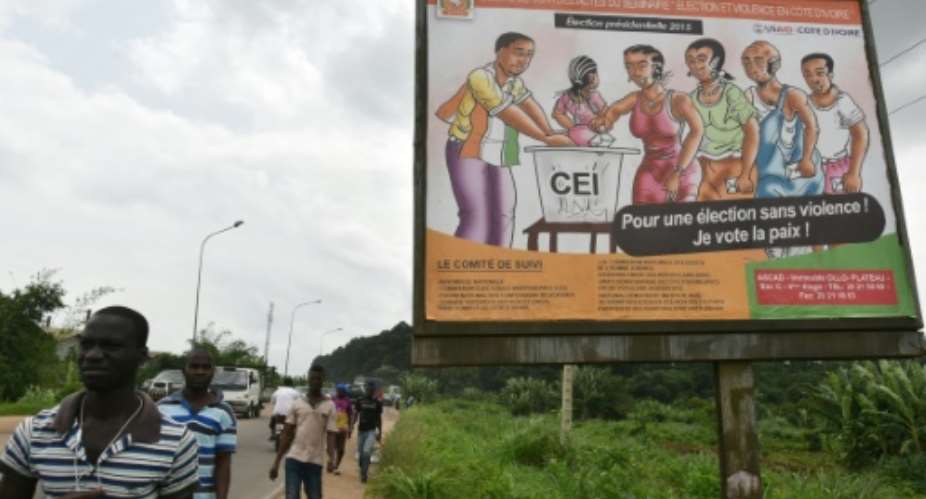 People walk past a banner errected by the Independent Electoral Commission IEC which reads,  For an election without violence, I vote for  peace in Abidjan on June 13, 2015.  By Sia Kambou AFPFile