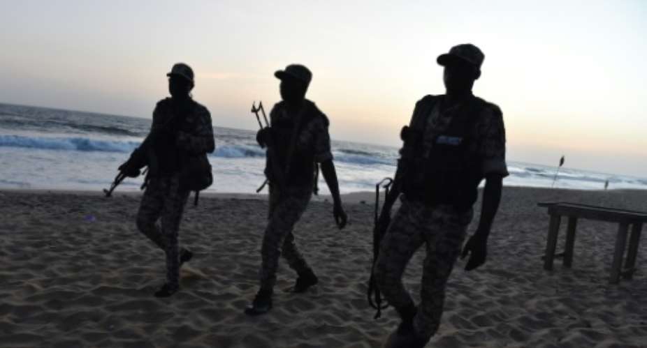 Ivorian soldiers walk on the beach after heavily armed gunmen opened fire on March 13, 2016 at a hotel in the Ivory Coast beach resort of Grand-Bassam.  By Issouf Sanogo AFP