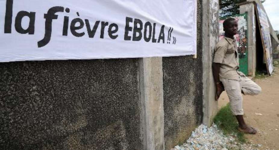 A young man stands near a banner reading ''Ebola fever!!'' ahead of a football tournament near the Koumassi sports center in Abidjan on August 10, 2014.  By Sia Kambou AFPFile