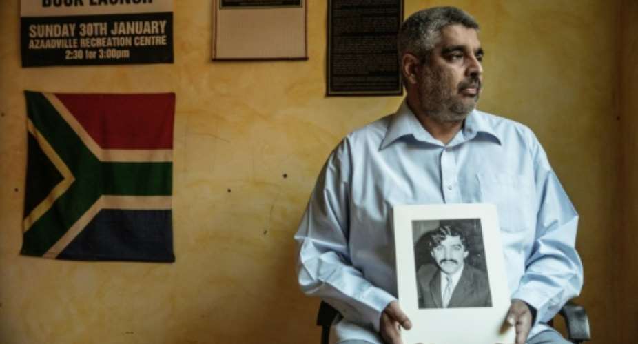 Imtiaz Cajee, the nephew of Ahmed Timol, an anti-apartheid activist brutally murdered in police custody in October 1971, holds a portrait of his uncle at his house on May 25, 2017 in Pretoria.  By GIANLUIGI GUERCIA AFP