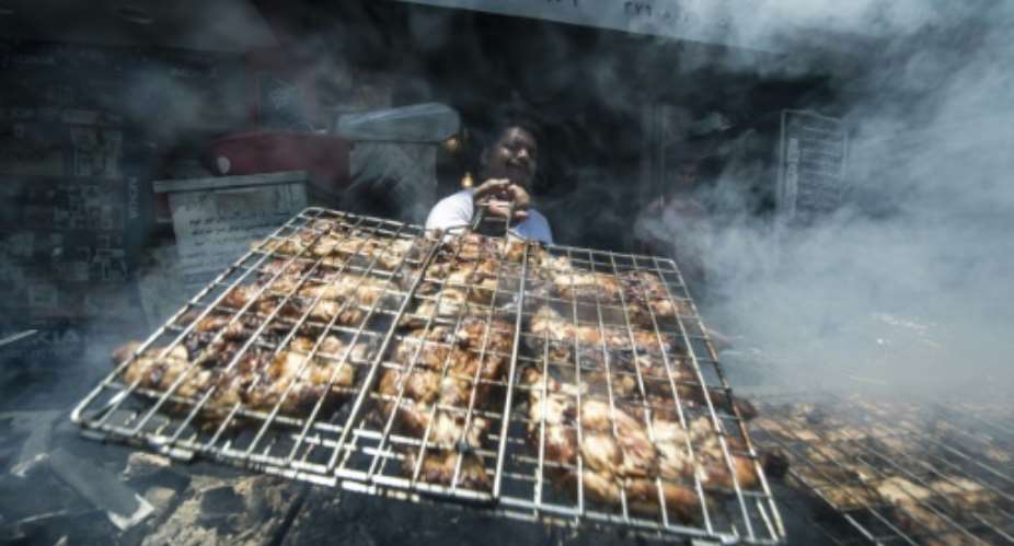 Egyptian cook Fathy grills chicken outside a restaurant in Cairo on June 21, 2016.  By Khaled Desouki AFP