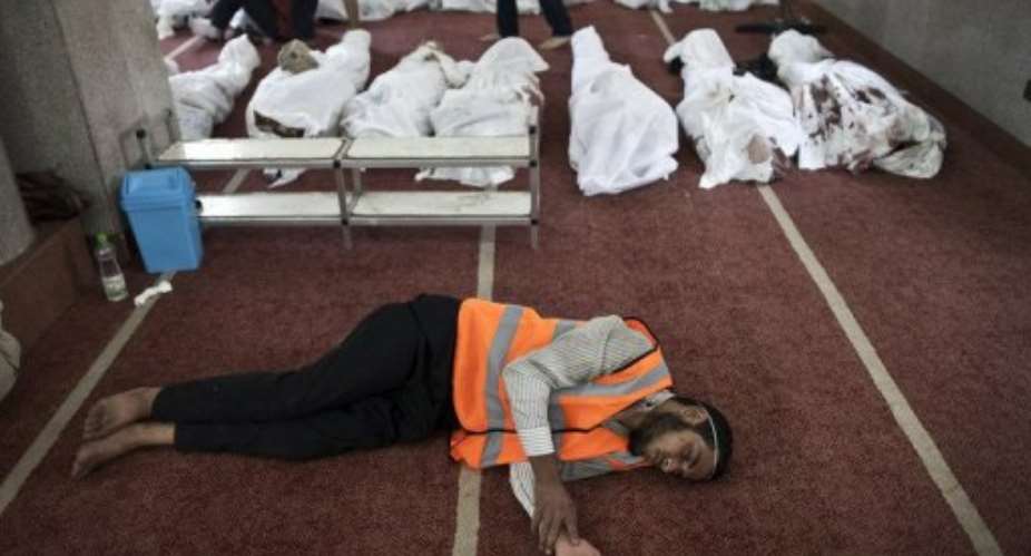 An Egyptian volunteer sleeps on the carpet of a mosque in Cairo where lines of bodies were laid out on August 15, 2013.  By Mahmoud Khaled AFP