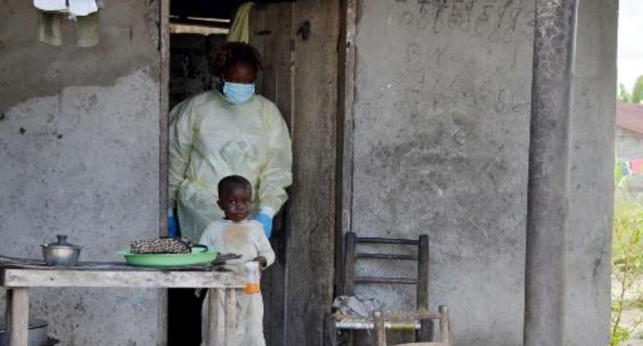 A medical worker leaves a house after visiting quarantined family members suffering from the Ebola virus, on October 16, 2014 in Monrovia.  By Zoom Dosso AFPFile