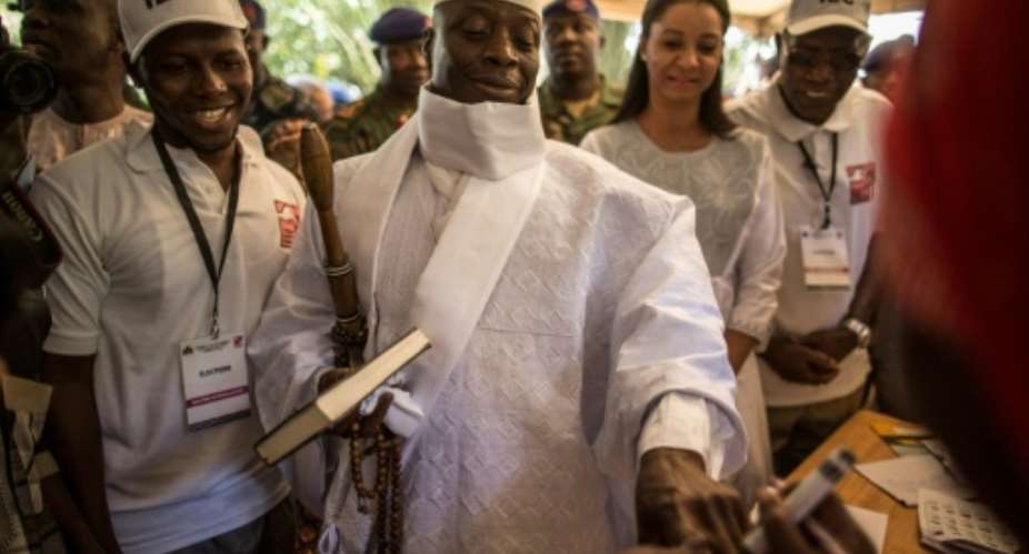 Incumbent Gambian president Yahya Jammeh C has his finger inked before casting his marble in a polling station in a presidential poll, in Banjul on December 01, 2016.  By MARCO LONGARI AFPFile