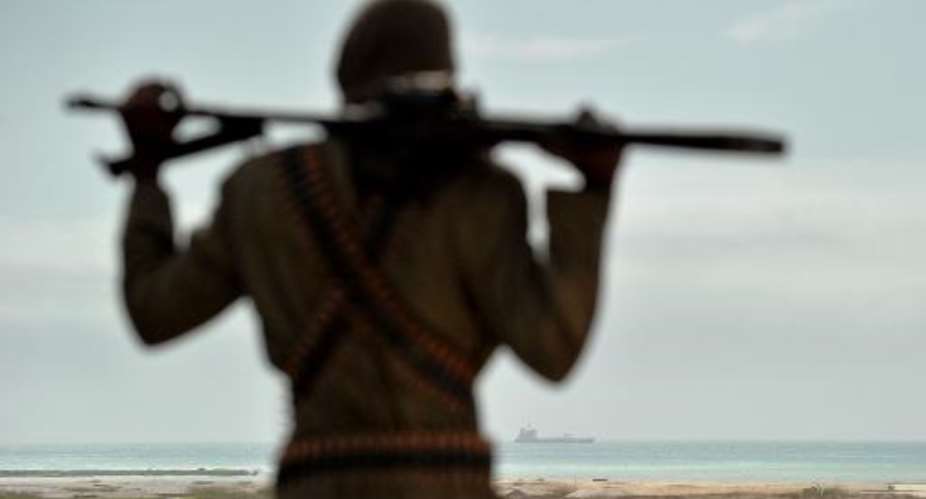 A Somali pirate boss watches a hijacked ship anchored off the coast near Hobyo on August 20, 2010.  By Roberto Schmidt AFPFile