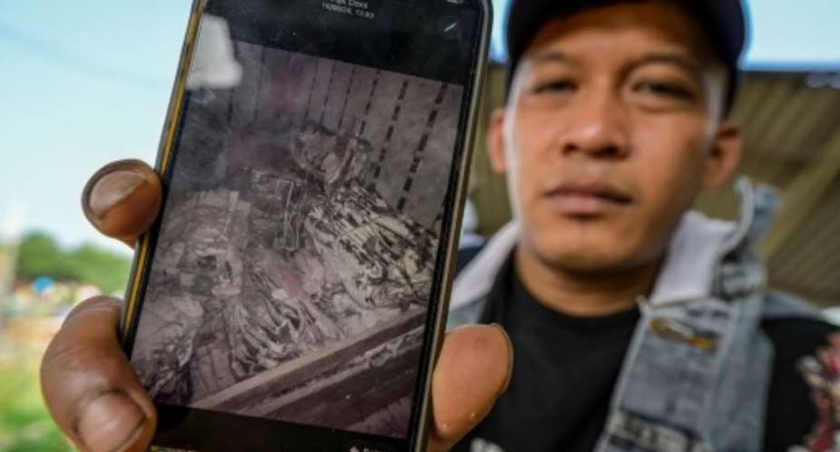 Indonesian fisher Jamaludin shows a photo of shark fins, taken during his time working on a Chinese tuna longliner, as he spoke to AFP near Cirebon, West Java.  By Bay ISMOYO (AFP)