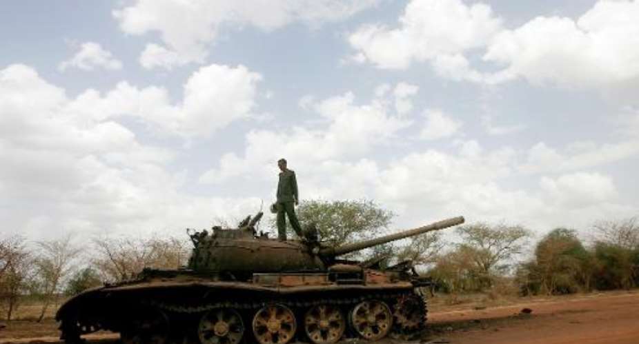 A Sudanese soldier stands atop a destroyed tank for the Sudanese Peoples Liberation Army SPLA of South Sudan in the oil region of Heglig on April 23, 2012.  By Ashraf Shazly AFPFile