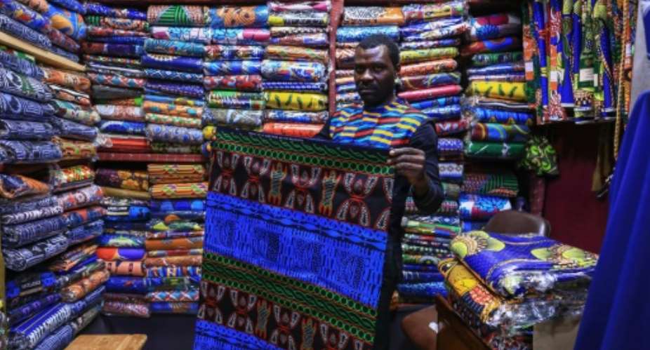 Iridescent: A trader holds a piece of the bright blue ndop ceremonial cloth in Bafoussam market in Cameroon.  By Daniel Beloumou Olomo AFP